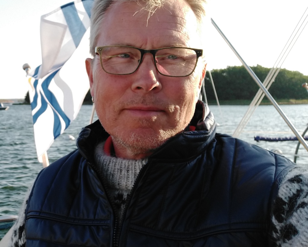 Kuvassa on Leo Junno. Leolla on silmälasit ja tummat vaatteet. Kuva on otettu ulkona.