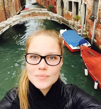 Kuvassa on Pia Lahtinen. Pialla on vaaleat hiukset poninhännällä ja silmälasit. Kuva on otettu ulkona, taustalla näkyy vettä ja veneitä.